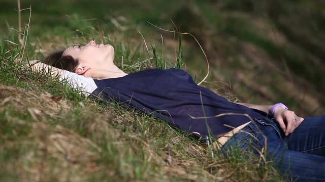 Young woman lies on the grass in the park on summer day
