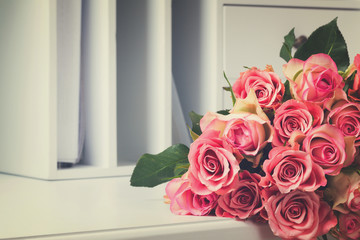 Bunch of pink fresh roses on white wooden table, retro toned