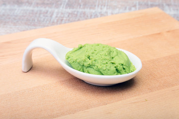 plate with Japanese wasabi sauce on wood background.