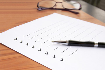 blank checklist on wooden table With a pen and glasses