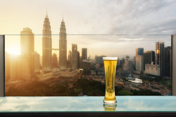 Obraz premium Piwo i piwo piankowe na stole w barze na dachu z wieżowca Kuala Lumpur w tle w Kuala Lumpur, Malezja.