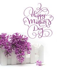 Beautiful spring lilac and a small fence on the white background and text Happy mothers day. Calligraphy lettering hand draw
