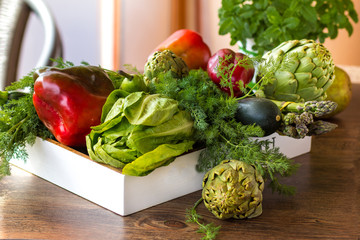 Variety of green vegetables and fruits in a crate on the table