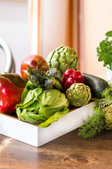 Variety of green vegetables and fruits in a crate on the table