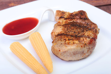 grilled pork chop with Cranberry sauce and Mini Corn cob preserved on plate on wooden board
