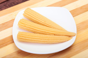 Mini Corn cob preserved on plate on wooden board.