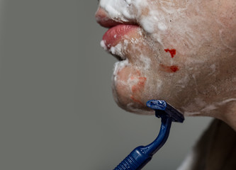 Closeup Man Shaving Razor Burn with blood. Man shaving using razor with cream foam. Guy removing face beard hair. Skin care and hygiene. Man was injured by a razor
