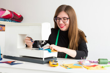 needlework and quilting in the workshop of a young woman - close-up on tailor work with a sewing machine and threads, fabrics, needles, pins, buttons