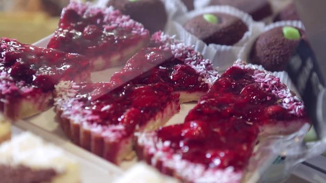 Shelf at a bakery with many different kinds of dessert - cakes, pastries, sweets,tarlets and pies.Wide assortment of fresh pastry at shop window.
