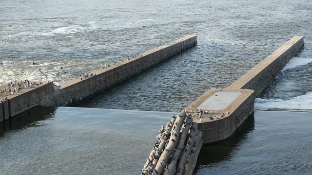 Modern purification station on a river bank with long concrete walls installed in water, hidden filters, and slowly moving waters in a sunny day in spring