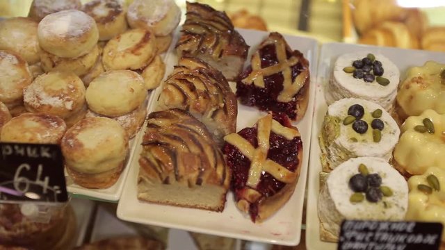 Shelf at a bakery with many different kinds of dessert - cakes, pastries, sweets,tarlets and pies.Wide assortment of fresh pastry at shop window.