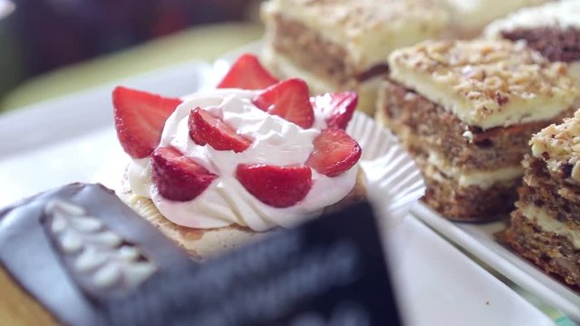 Shelf at a bakery with many different kinds of dessert - cakes, pastries, sweets,tarlets and pies.Wide assortment of fresh pastry at shop window.