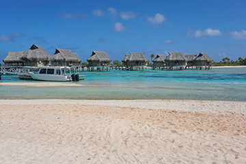 Tropical overwater bungalows in the lagoon seen from a sandy beach shore, atoll of Tikehau, Tuamotu, French Polynesia, south Pacific ocean