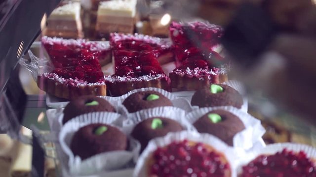 Shelf at a bakery with many different kinds of dessert - cakes, pastries, sweets,tarlets and pies.Wide assortment of fresh pastry at shop window.