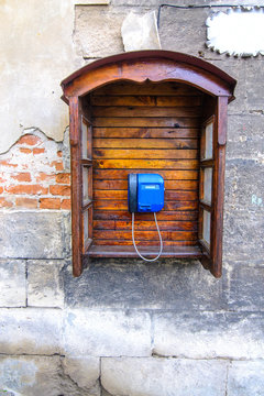Retro telephone with wooden phone booth on a cracked concrete vintage stone wall background