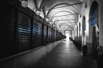 Fototapeta premium black and white arcade selective color blue light closed shops padova veneto italy