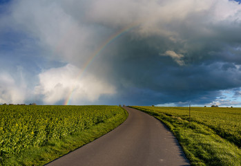 Rainbow over the asphalt country road