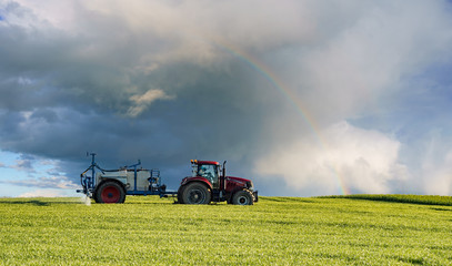 farm tractor carrying spraying chemicals on a spring field