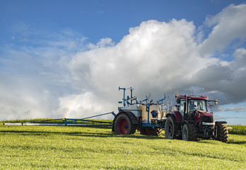 farm tractor carrying spraying chemicals on a spring field