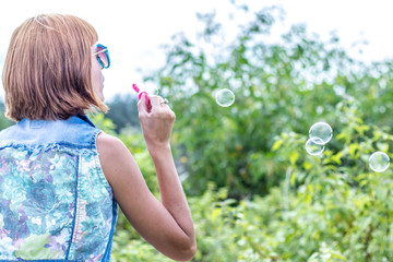 Beautiful young woman blowing bubble in outdoor, nature, near the ocean. Tropical magic island Bali, Indonesia.