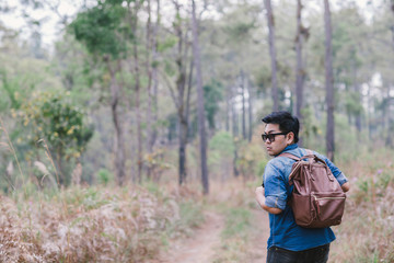 A male traveller with his sunglasses and backpack in the pine forest, Thailand