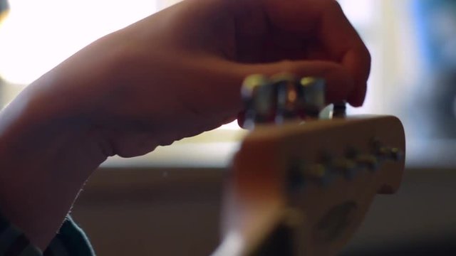 Slow motion. Close-up of guitar playing. Guitarist hits the strings of the guitar. Skill. Playing a musical instrument. Stringed Musical Instruments. Black guitar with abrasions. Ukulele Guitar