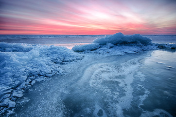 Fototapeta na wymiar Abstract frozen winter sunrise seascape with ice and colored the sky.