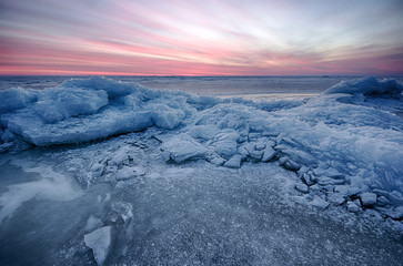 Naklejka na ściany i meble Abstract frozen winter sunrise seascape with ice and colored the sky.