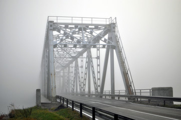 Autumn morning scene. Fogbound bridge over the river.