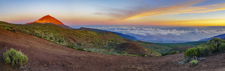 The hillside of the teide volcano lit by the setting sun, down the ocean and flowing sea of clouds