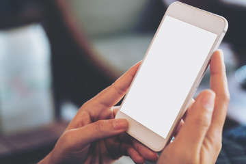 Mockup image of hand holding mobile phone with blank white screen in vintage cafe