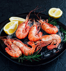 Shrimps with lemon and greens on a dark background