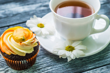 Still life with cup of tea and cake on the wooden background