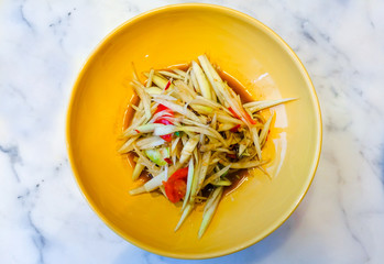 Spicy green papaya salad with Thai anchovy sauce (Traditional Thai food) on yellow plate