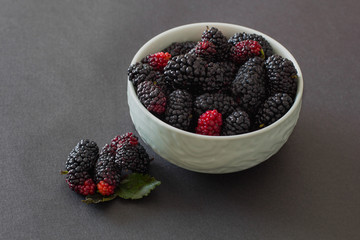 Fresh organic vietnamese black mulberry on grey background in green bowl