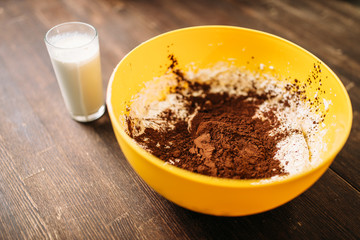 Bowl with dough, chocolate powder, glass of milk