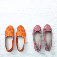 Flat lay fashion set: colored slippers shoes on white wooden background. Top view.