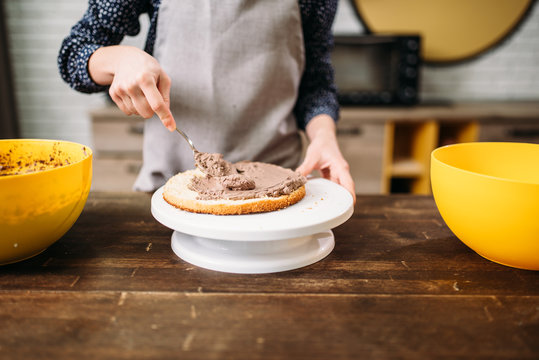 Female hands smears cake with chocolate cream