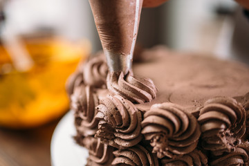 Decoration of chocolate cake with culinary syringe