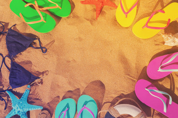 Summer beach fun - frame on sand with sandals and swimming suits, retro toned