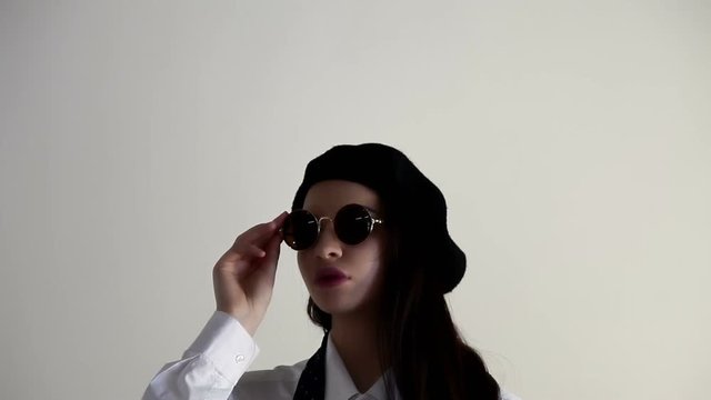 A Young woman in shirt, sunglasses and beret, on the white background