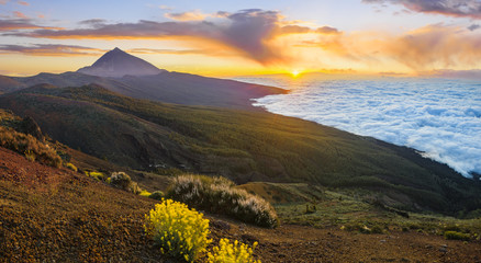 The hillside of the teide volcano lit by the setting sun, down the ocean and flowing sea of clouds