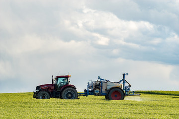 farm tractor carrying spraying chemicals on a spring field	