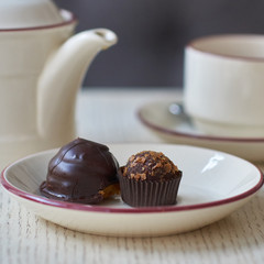 Chocolate petit four, cup and kettle of tea