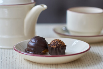 Chocolate petit four, cup and kettle of tea