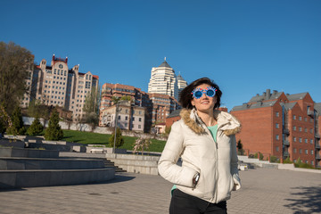 Portrait of a smiling girl in a funny sunglasses with flying hair during a walk