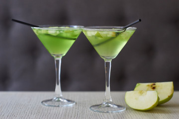 Two glasses of apple martini and apple slices on table in cafe