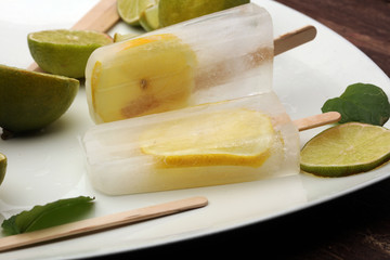 Healthy lime mint popsicles with fresh lime slices on wooden background