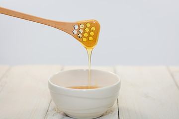 With a honey spoon a bowl is filled with flower honey