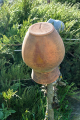 Old clay jug on a wooden fence.